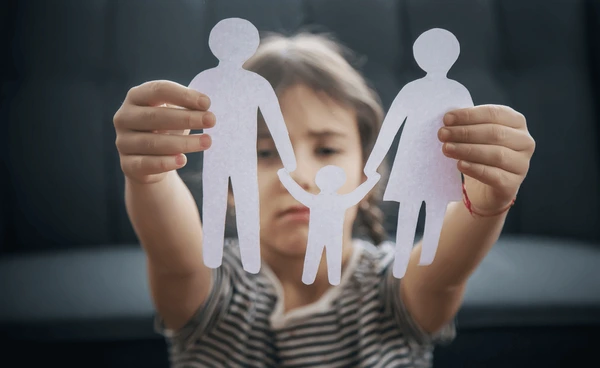 child upset holding paper cutting of parents. Child custody